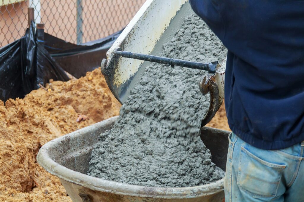 Concrete being poured from a truck into a concrete pump at a construction site